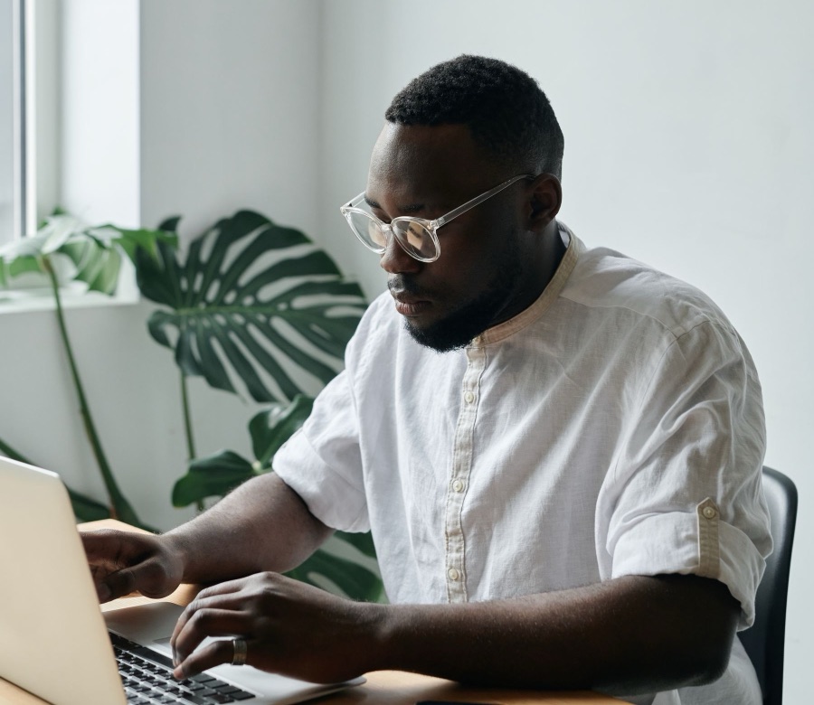 Man in glasses working on his laptop at a desk
