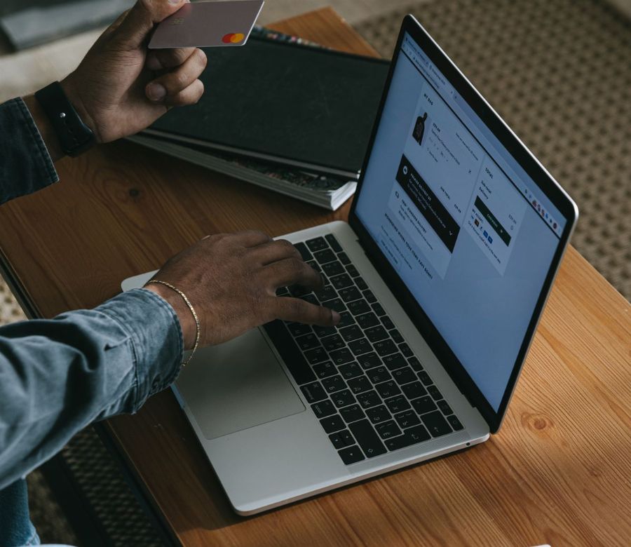 Person paying online with a card on a laptop